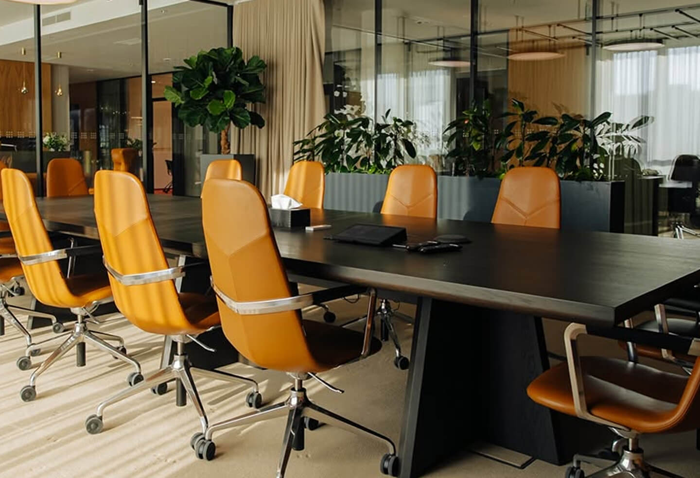 Zasedací místnost s oranžovými židlemi a rostlinami