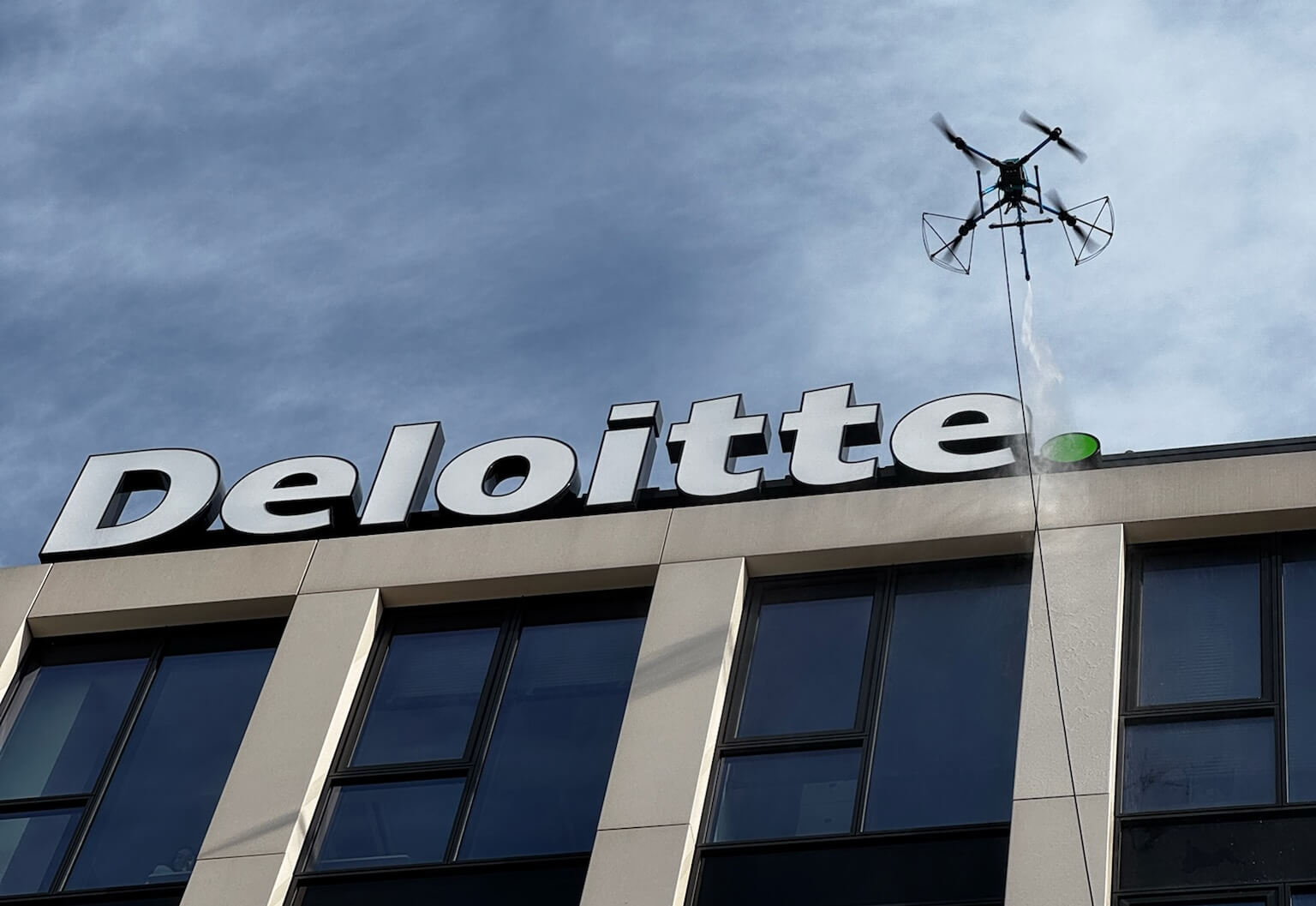 Dron čistí fasádu budovy Churchill Square s logem Deloitte