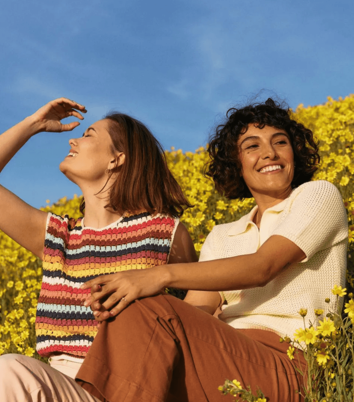 Two women sitting together in a field on a sunny day