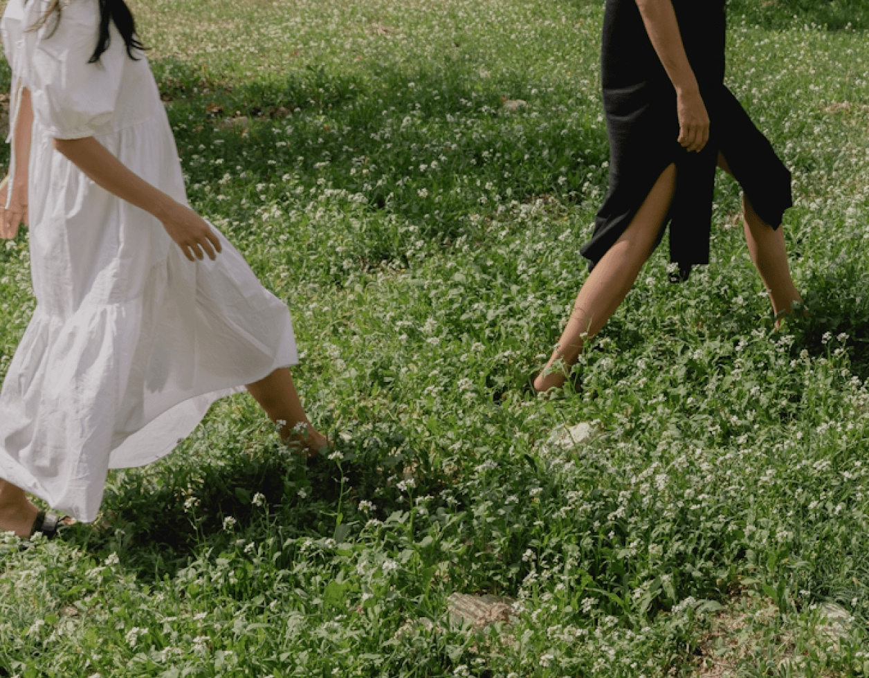 Two women walking together through a field of wildflowers