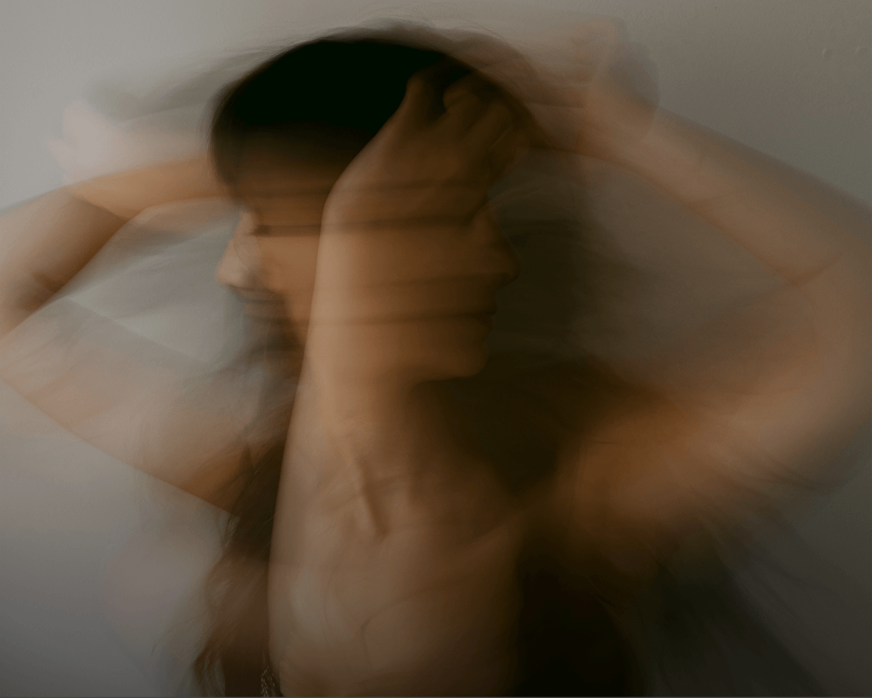 Moion-blurred woman with hands on their head, representing mental health support