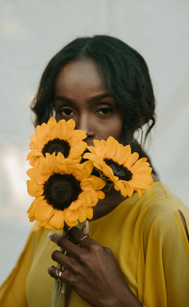 Woman holding a sunflower in front of her face