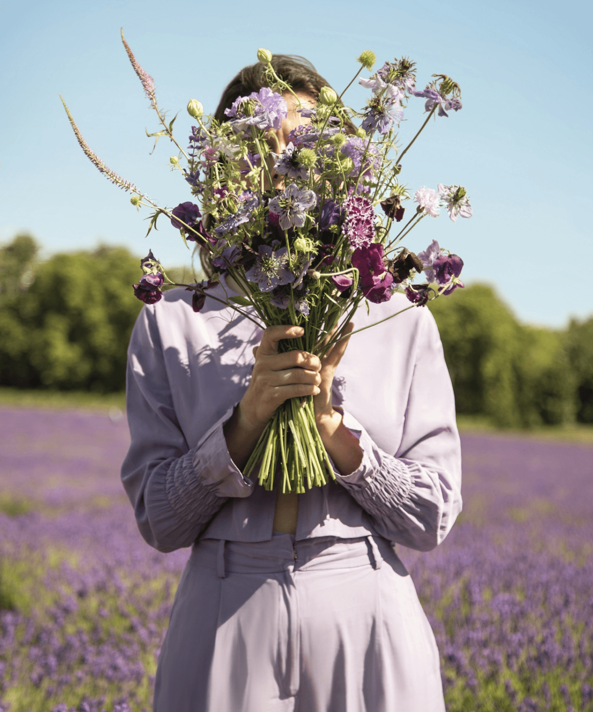 Woman holding a bouquet of flowers in front of their face