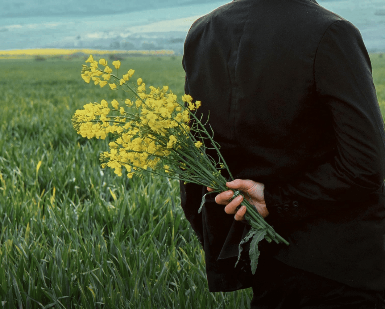 Person holding yellow flowers behind their back