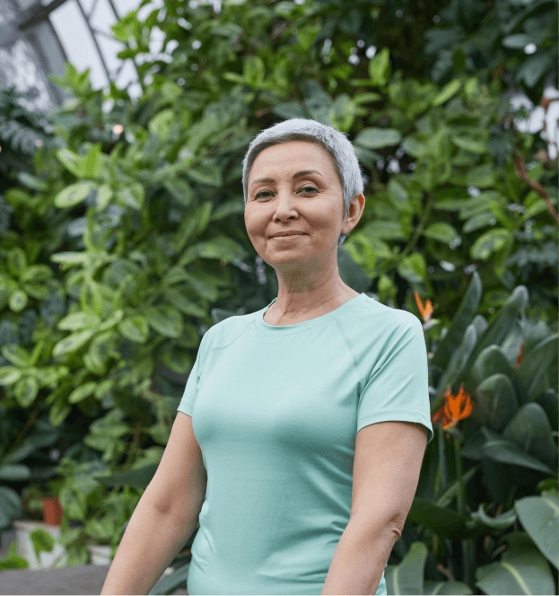 Person standing in a greenhouse surrounded by plants