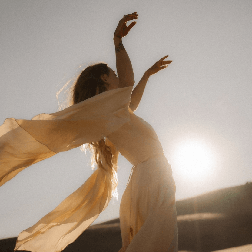 Woman standing outdoors with fabric flowing in the wind