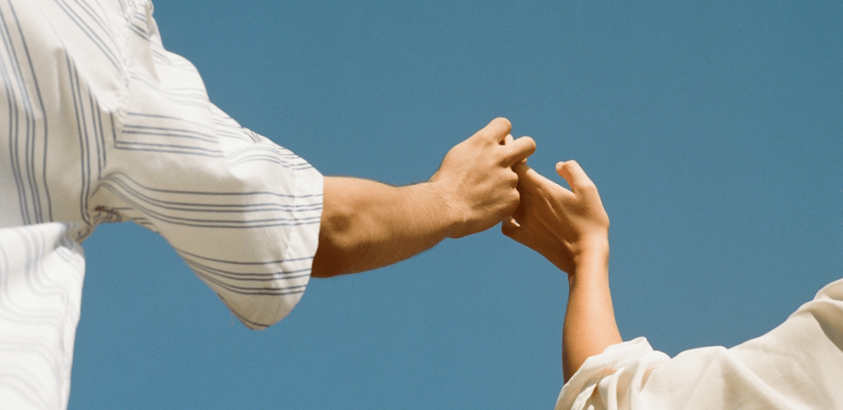 Two people reaching toward each other with outstretched hands