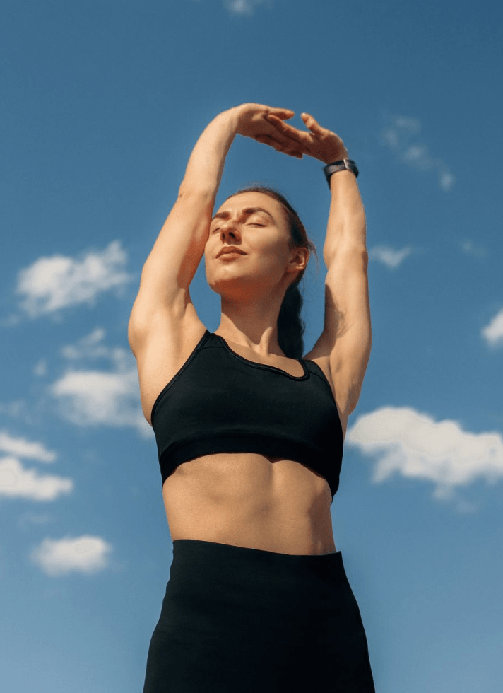 Woman stretching outdoors beneath a blue sky