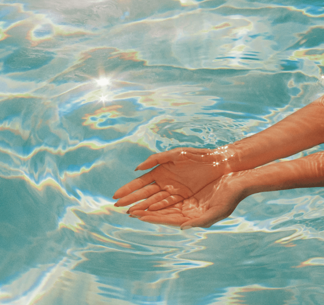 Hands moving through water in a calm, reflective setting