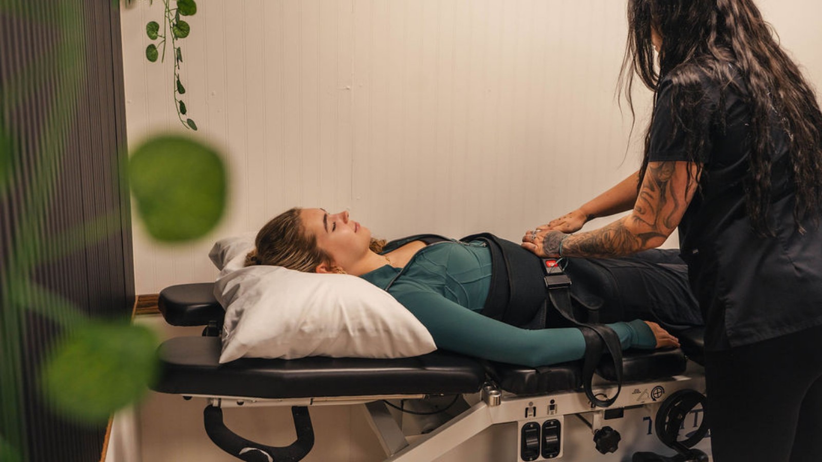 Kee Health clinician fastening a padded decompression harness around the waist of a patient lying on a spinal decompression table