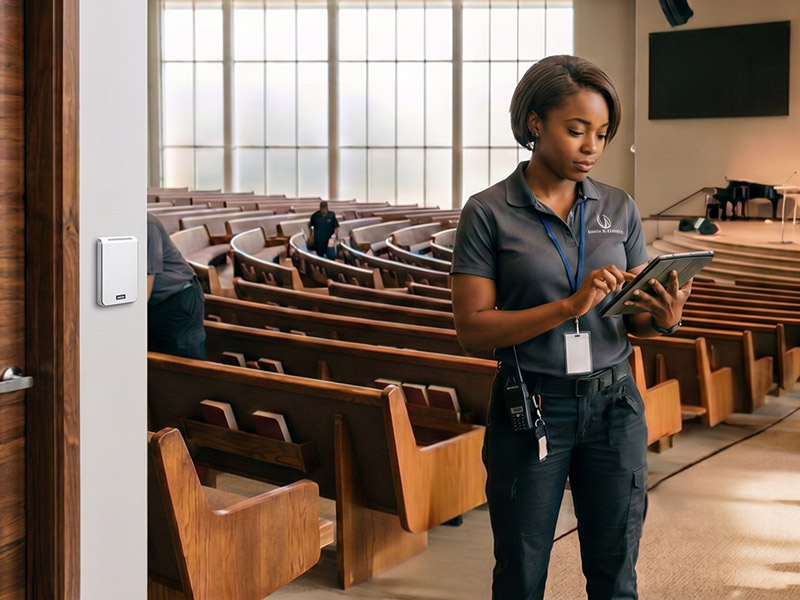 A facilities staff member wearing a lanyard looks at a tablet device