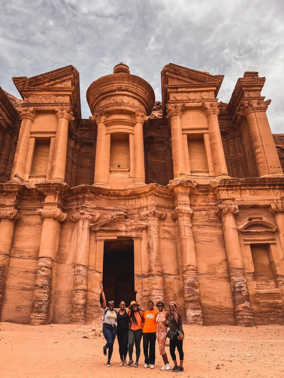 Group of six women posing in front of Petra's ancient rock-cut architecture in Jordan.