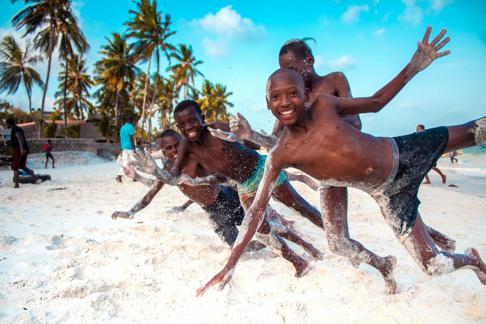 Kids playing and laughing on a white sand beach.