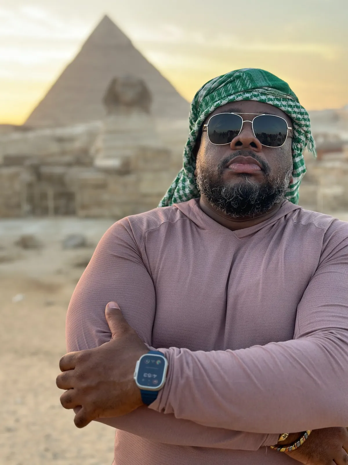 A Haitian Nomad traveler with arms crossed in front of the Sphinx at sunset, Egypt
