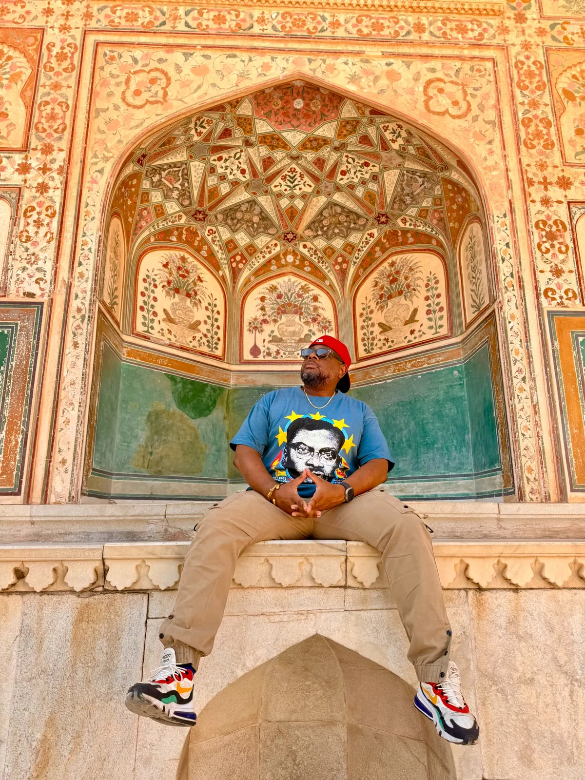 A Haitian Nomad traveler seated beneath a painted arch at Amber Fort in Jaipur, India