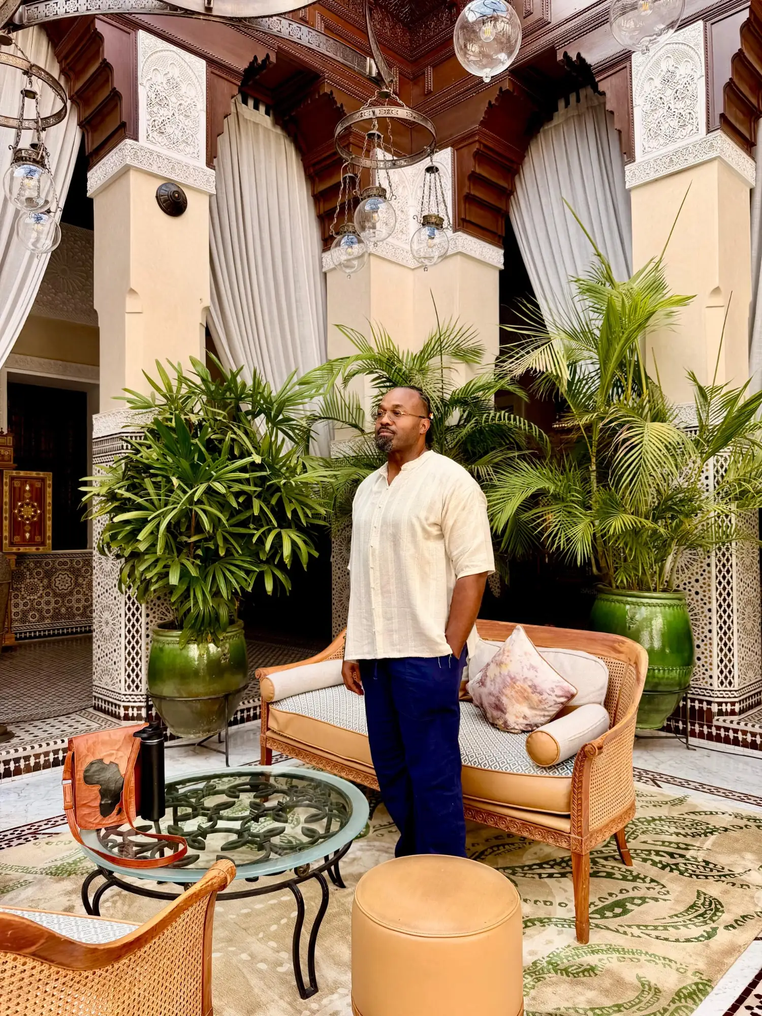 A Haitian Nomad traveler standing in a palm-filled riad courtyard in Marrakech