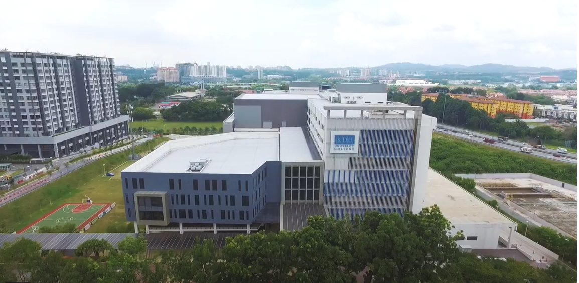 Aerial view of KDU University College in Malaysia, showcasing the modern campus buildings, a sports court, and surrounding greenery against a backdrop of urban and suburban areas.