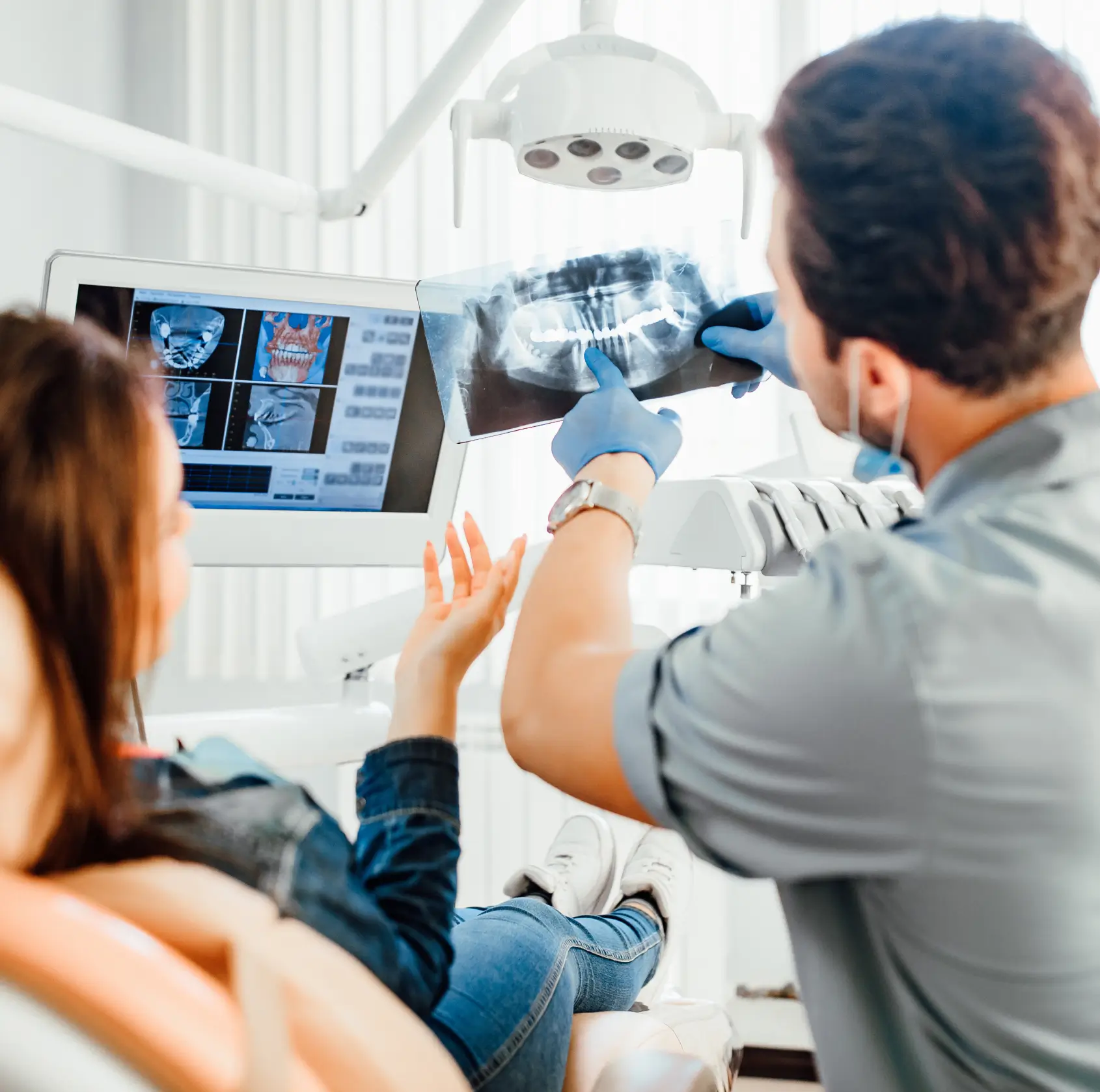 Dentist showing a patient dental X-rays and explaining treatment while in the dental office chair. La Perle Dental Center in Edmonton, AB TST 3T9