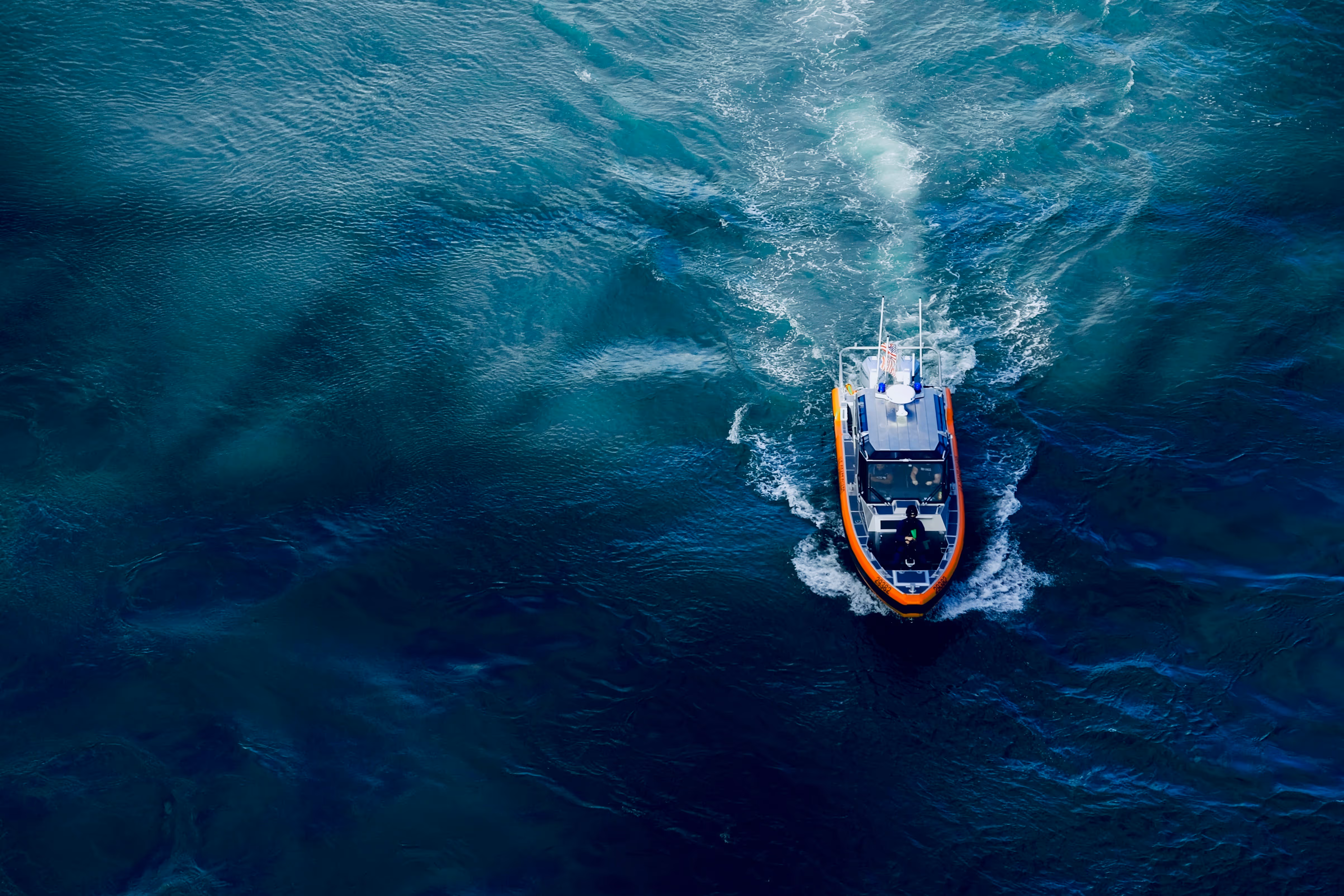 Aerial view of a small vessel underway on dark open water