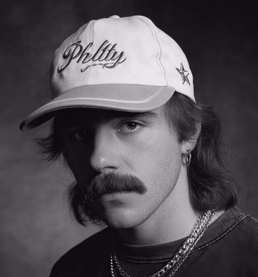 Black and white portrait of a man in a cap with chains and a hoop earring