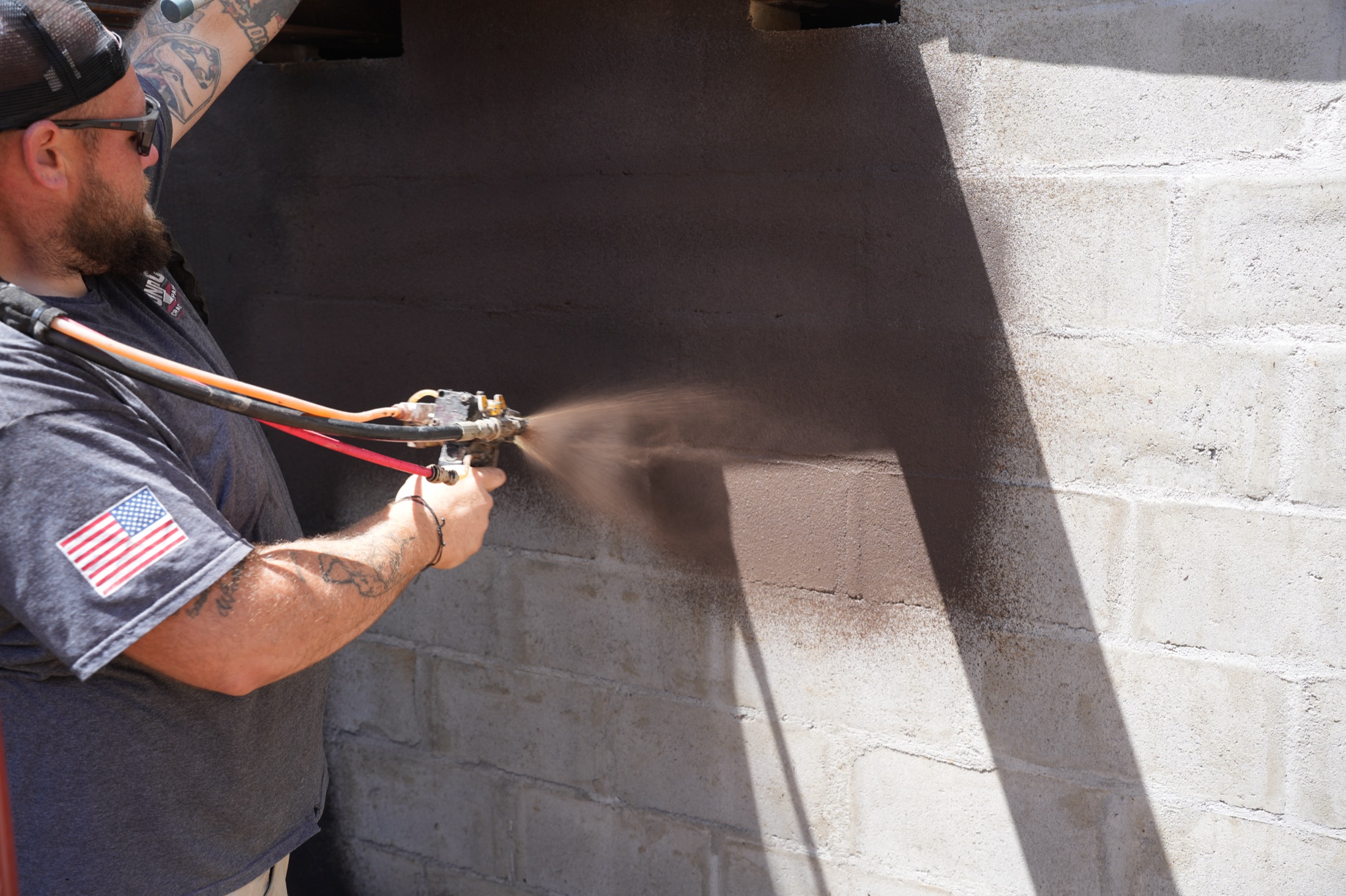 Foundation Crack Repair technician spraying waterproofing coating on a basement block wall