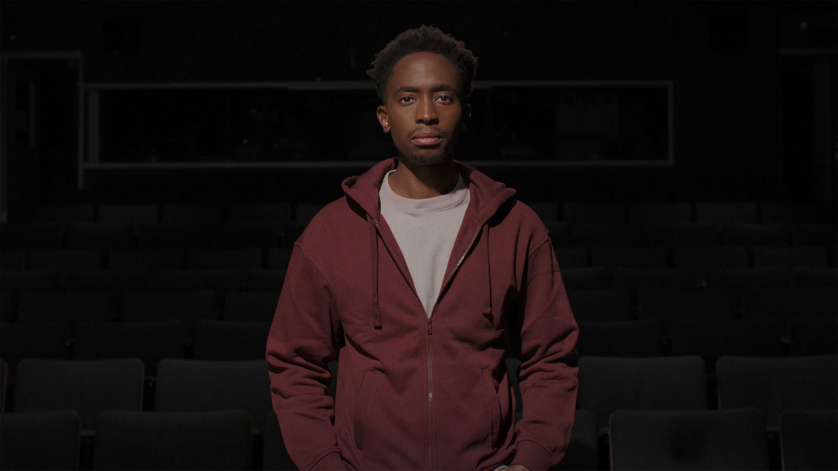 A Black teenager in an auditorium.