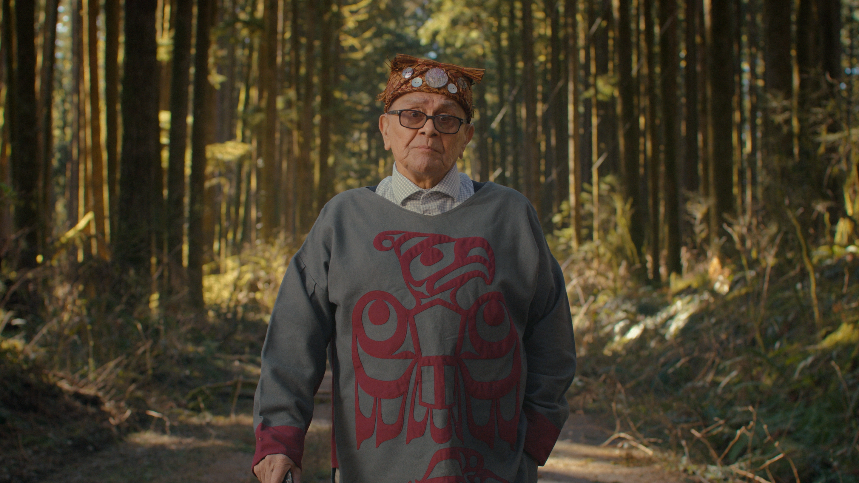 An Indigenous elder standing in a forest.
