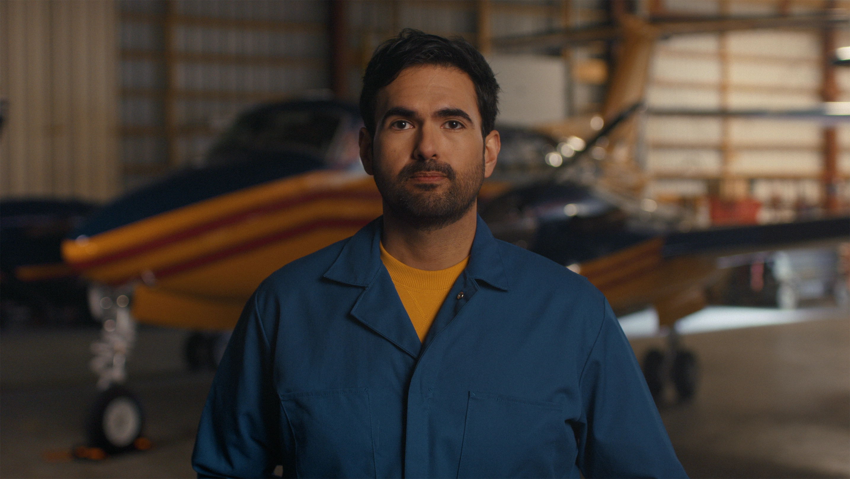 A middle-aged man in coveralls in front of an airplane.