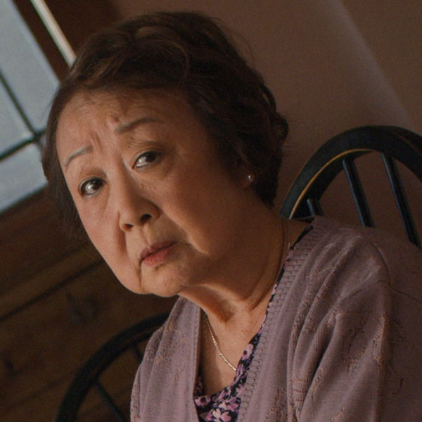 An Asian grandmother sitting in a chair at home.