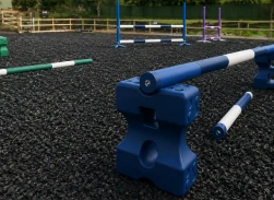 Blue resn bound obstacle on black rubber surface with white and colored poles arranged nearby.