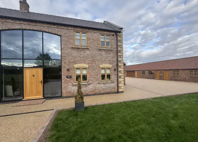 Modern resn bound house exterior with brick facade, large windows, and grassy area outside.