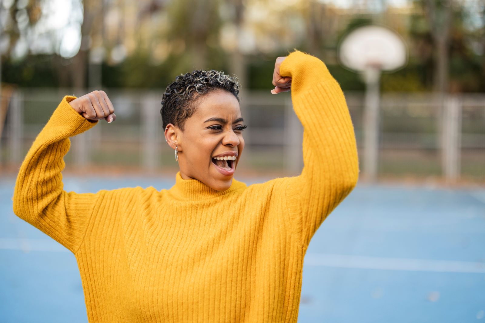 woman in yellow sweater doing bicep flex