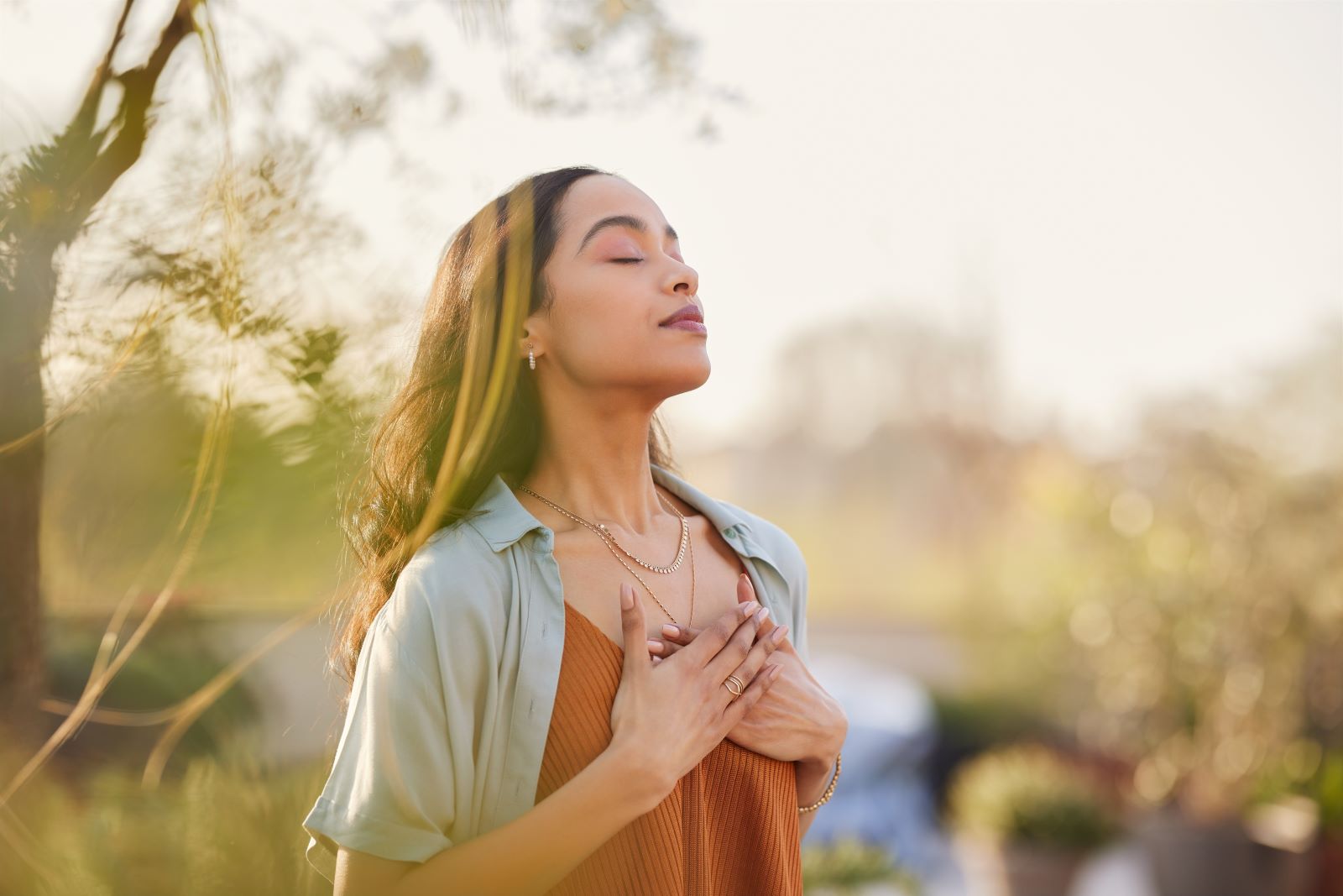 woman with hands on chest with nature background