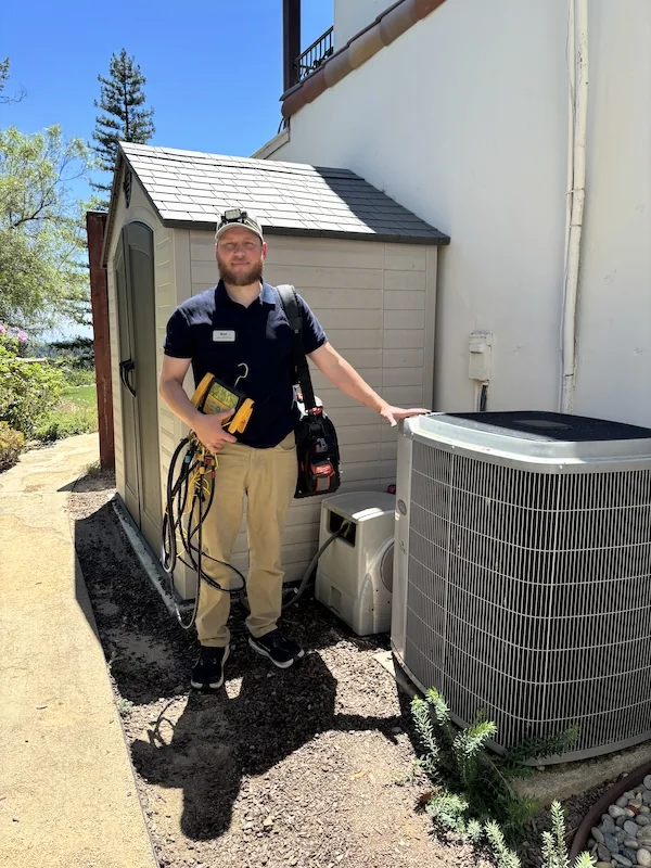 Plug-In Services technician beside outdoor HVAC equipment