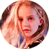 Young girl with long blonde hair and red lipstick looking into the camera.