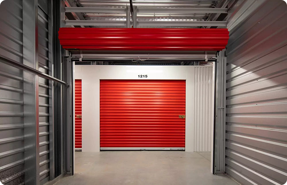 Indoor Stack N Stor, interior view of a self-storage facility with red roll-up doors, including one labeled 1215.