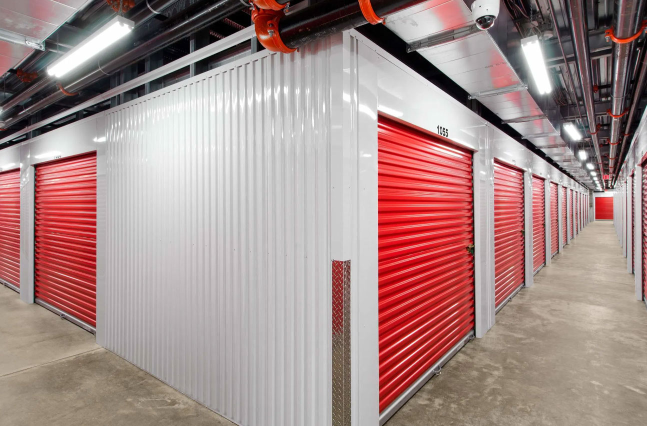 Pack N Stor East Fishkill NY Indoor storage facility with white walls and rows of red roll-up doors on both sides.