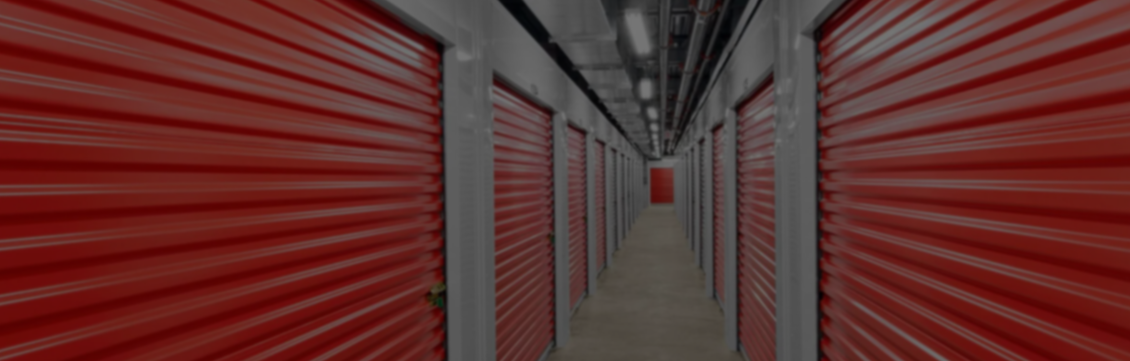 Pack N Stor Self-Storage Long hallway with rows of red storage unit doors inside a storage facility.