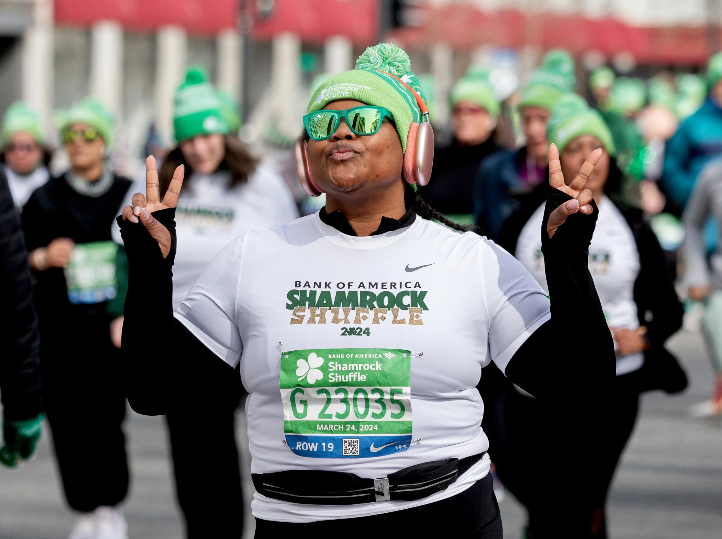 A runner putting up 2 peace signs during The Bank of America Shamrock Shuffle