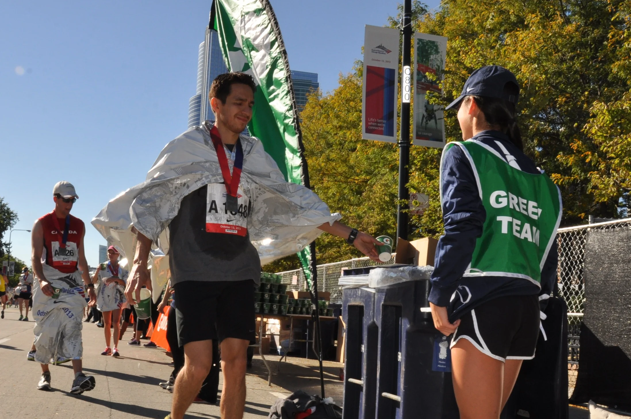 A member of the Green Team helping a Bank of America Chicago Marathon runner recycle a cup