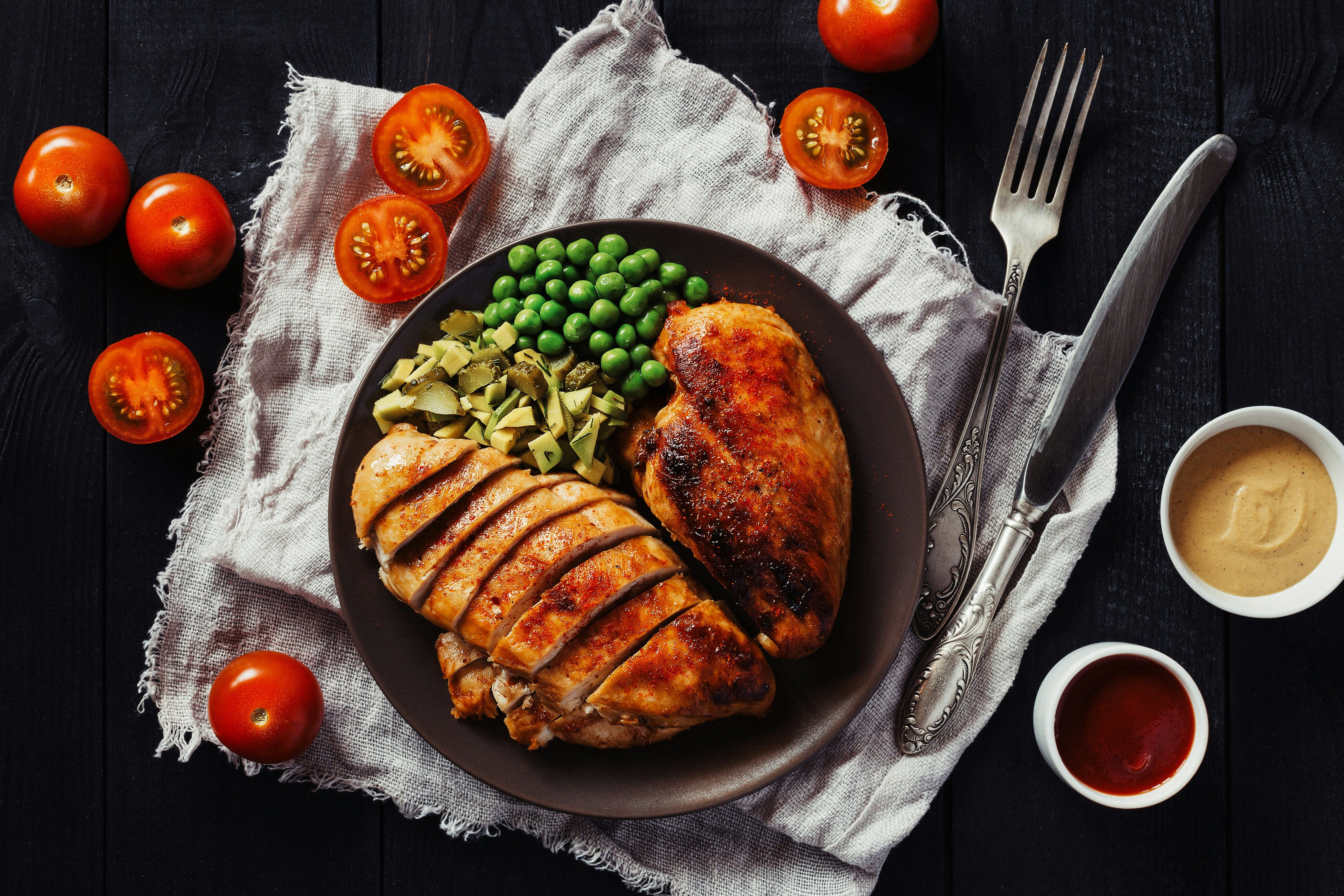 Grilled chicken and vegetables on a dark background, representing a balanced meal for cutting or bulking