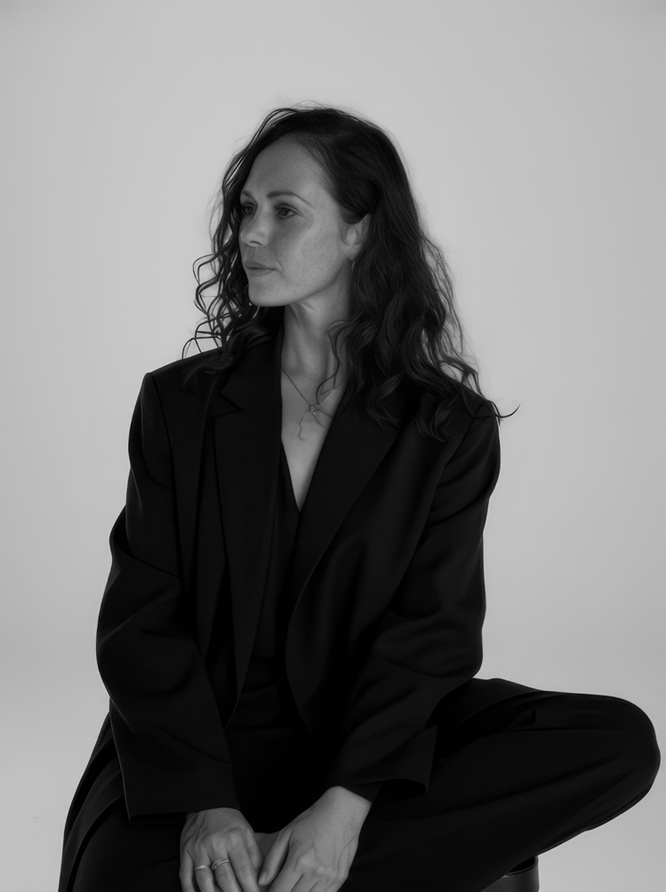 Portrait Photo of Arna Lane, Owner of Arcana Healing, sitting on a chair and looking to the side