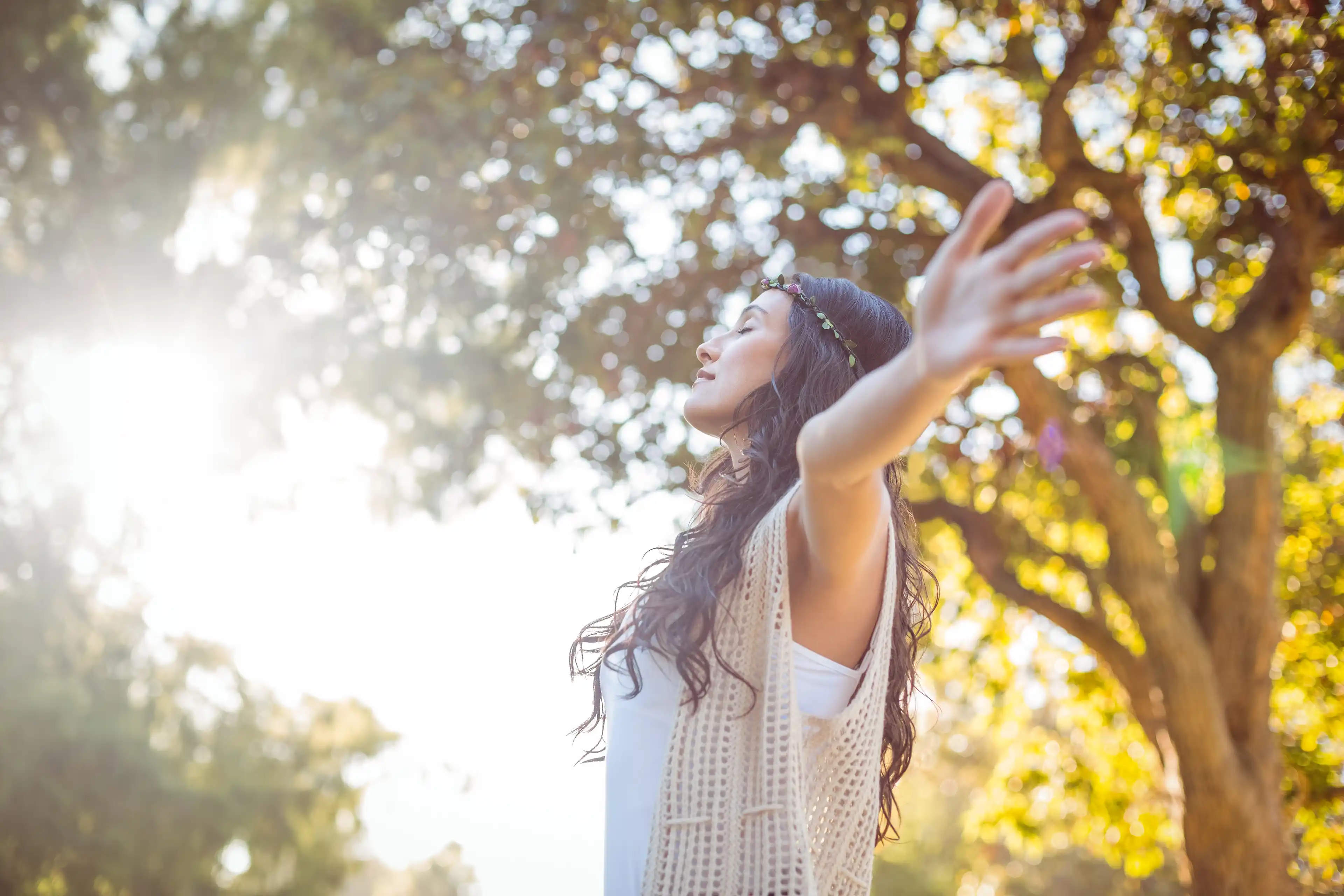 Woman standing in the light with her arms open, taking in the sun