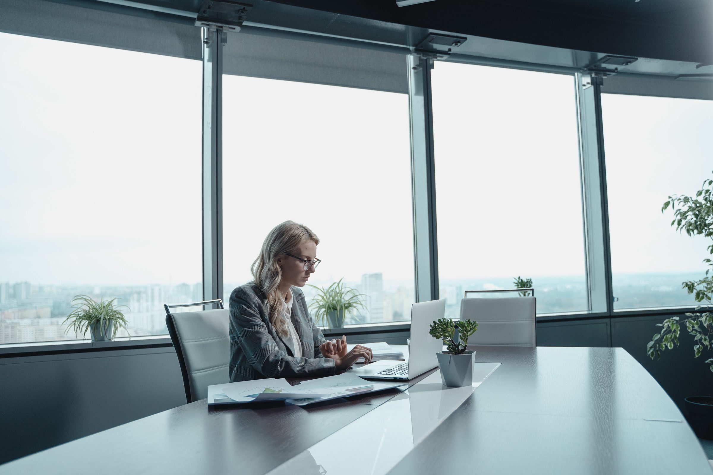 A professional woman working at a laptop in a high-rise office