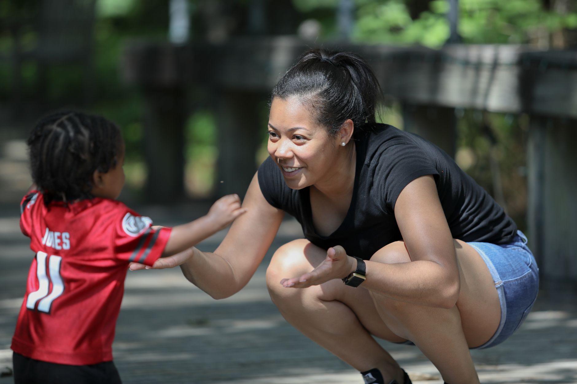 Mother playfully engaging with her son in a sunny park setting.