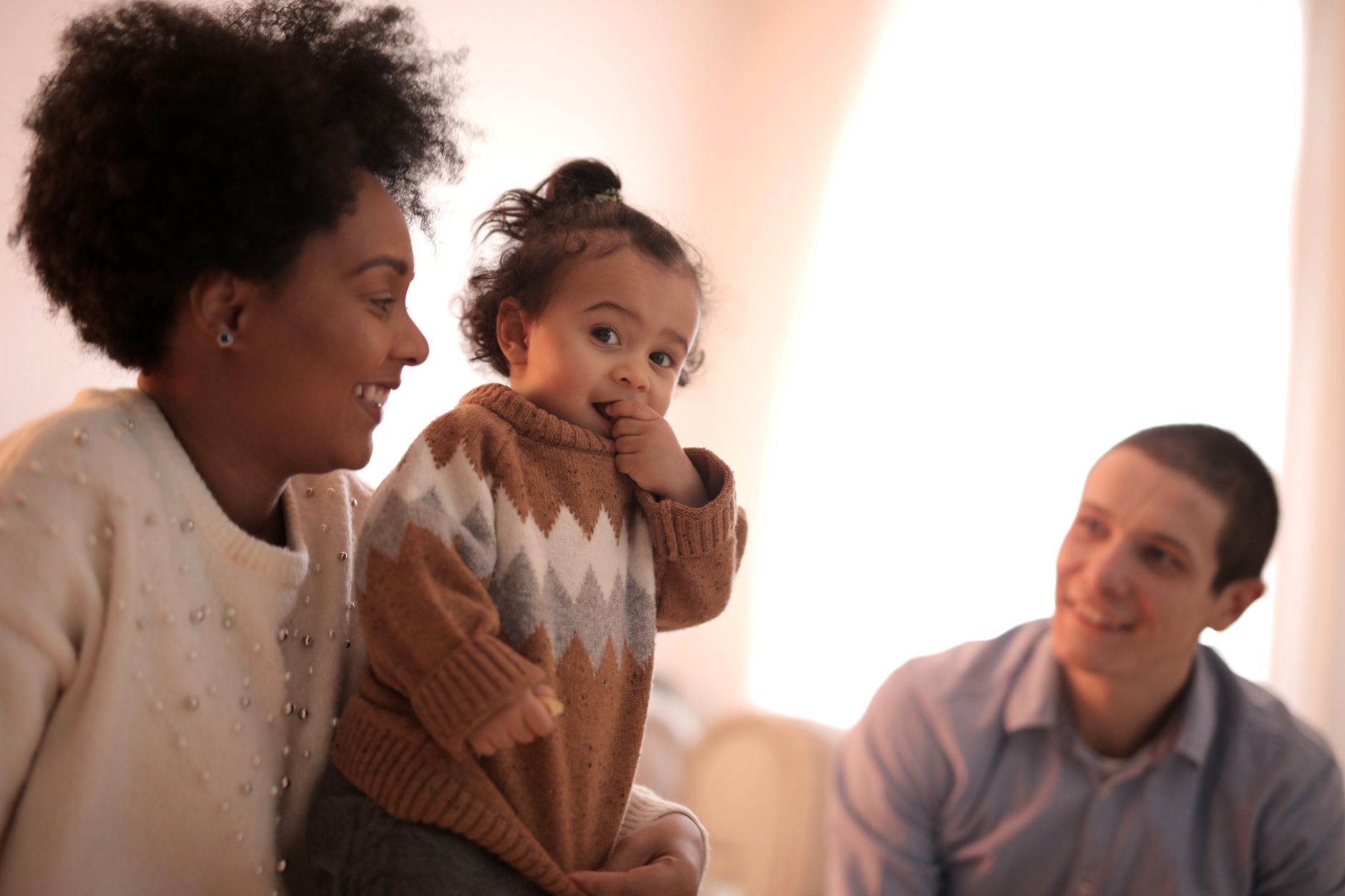 A joyful family enjoying a moment together indoors with a toddler.