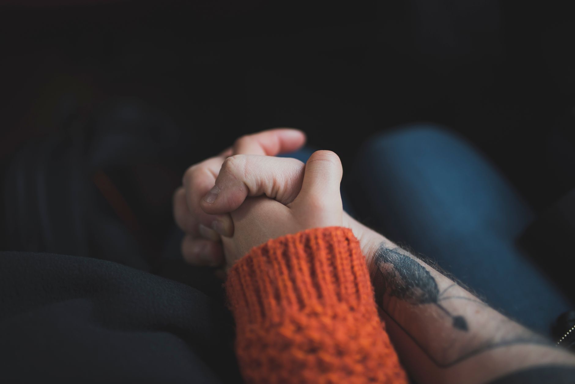 Two hands holding each other, symbolizing love and support with a warm tone.