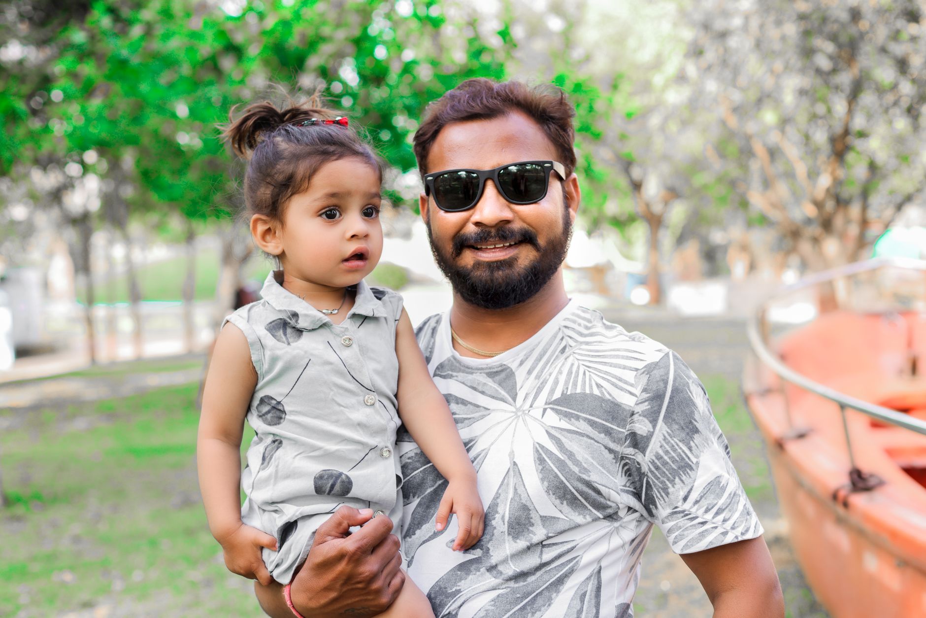 Smiling father holding daughter outdoors on a sunny day in Palanpur, India.