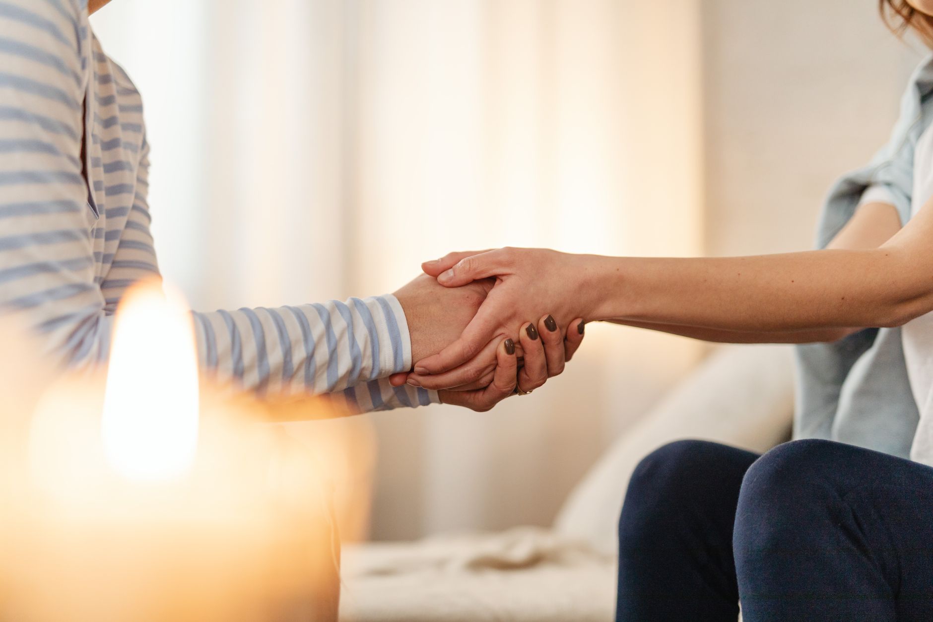 Close-up of a comforting hand hold, symbolizing support and affection, with a warm ambiance.