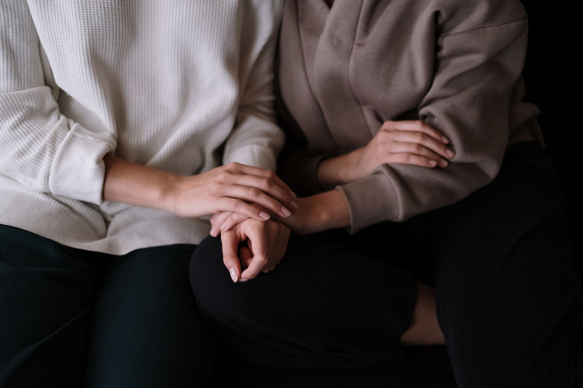 Two individuals sitting together, providing comfort and support with gentle touch.